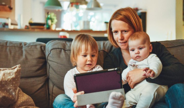 Mother with children playing with tablet on couch